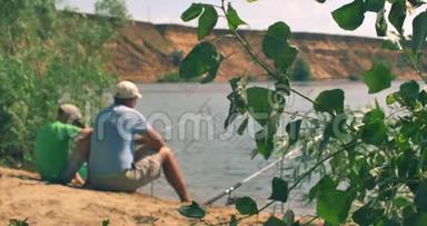 一对幸福的<strong>父子</strong>坐在河岸上，<strong>钓鱼</strong>，爸爸和儿子早上在<strong>钓鱼</strong>。 家庭幸福。